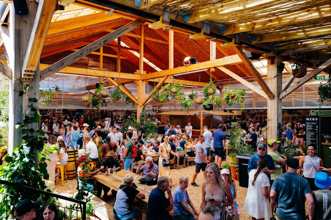 Crowded outdoor market with wooden beams and greenery