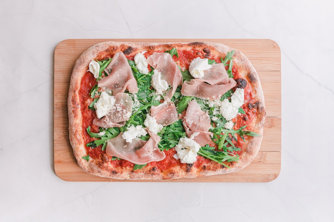 a pizza on a cutting board topped with meat and veggies