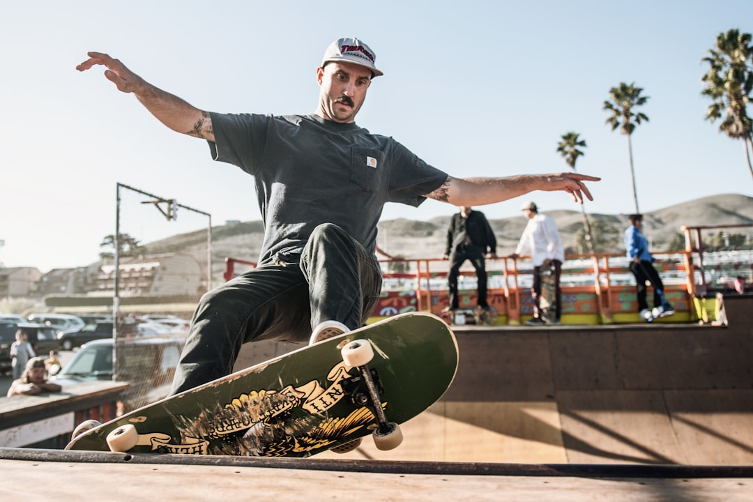 man in black crew neck t-shirt and black pants sitting on skateboard during daytime