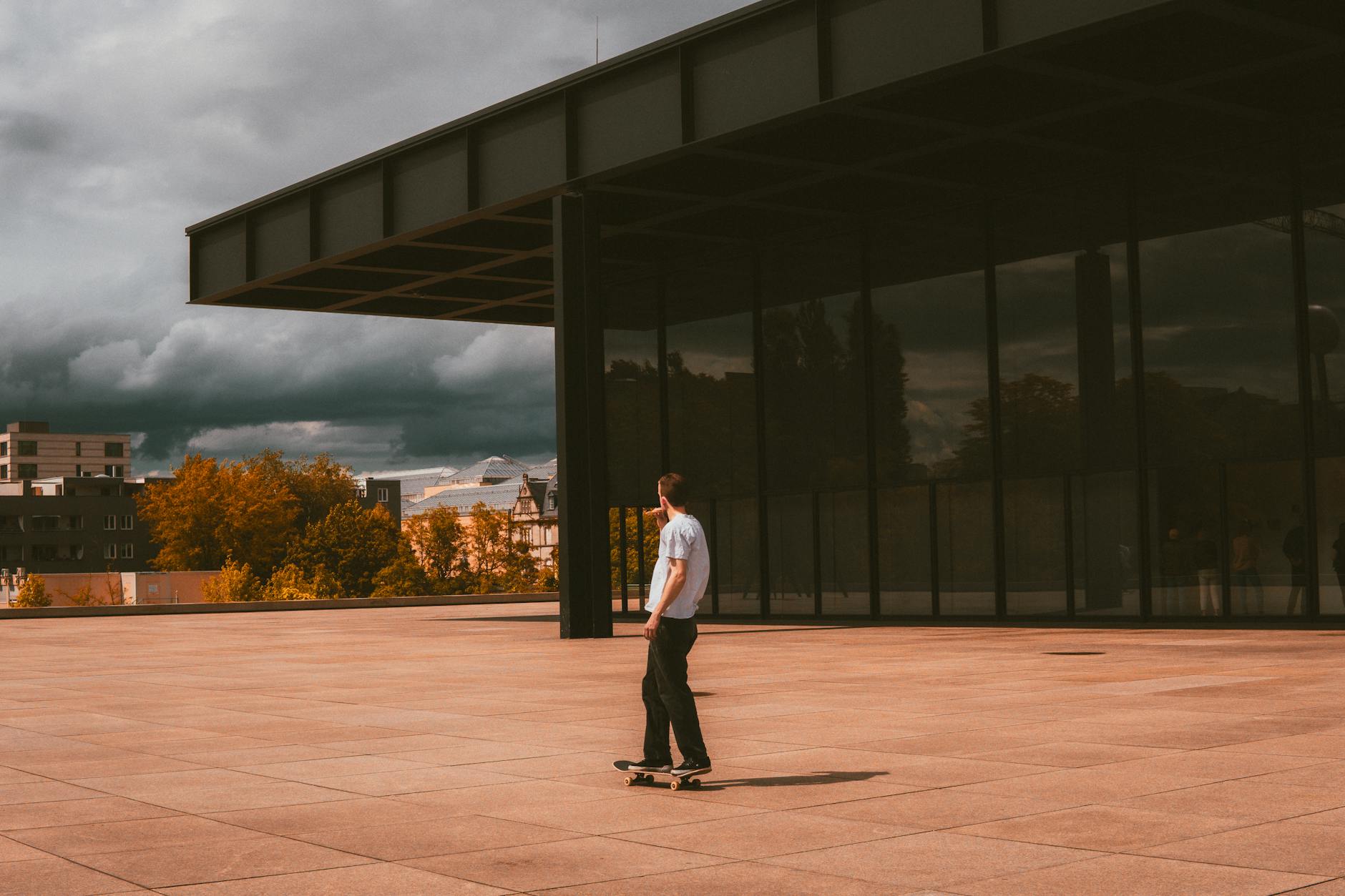 A skateboarder glides by modern architecture in Berlin on a warm day.