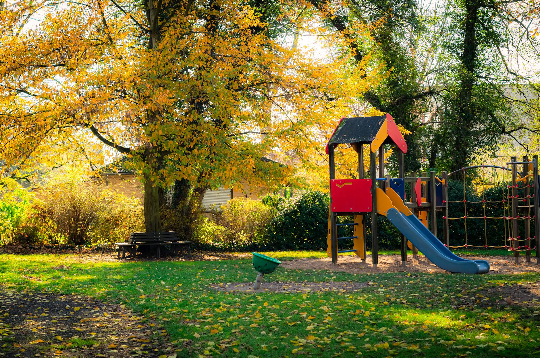 Bright playground equipment with autumn leaves in a park setting.