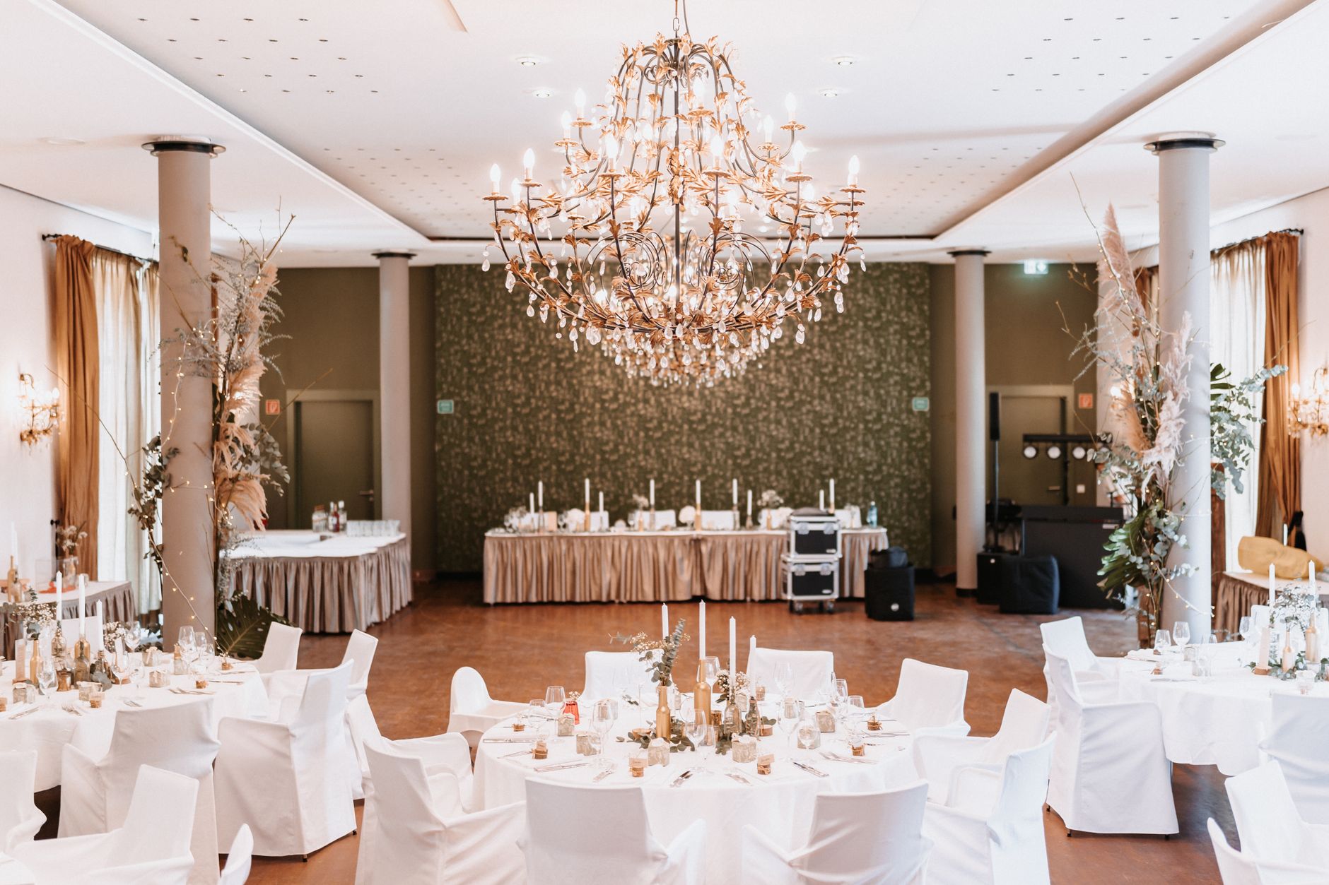 Beautifully decorated wedding reception with round tables and a grand chandelier.