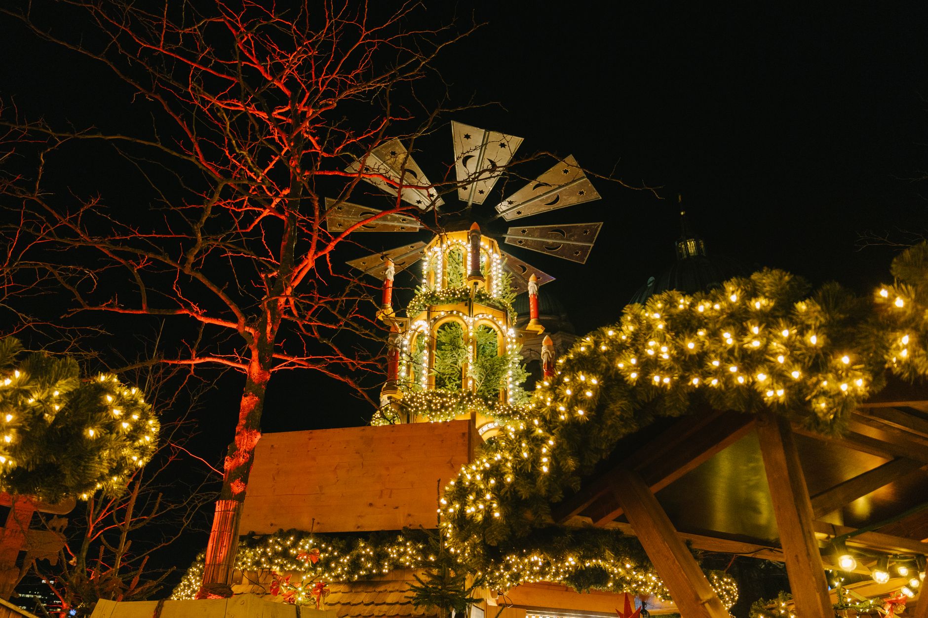 Explore Berlin's Christmas market with stunning lights and festive decorations under the night sky.