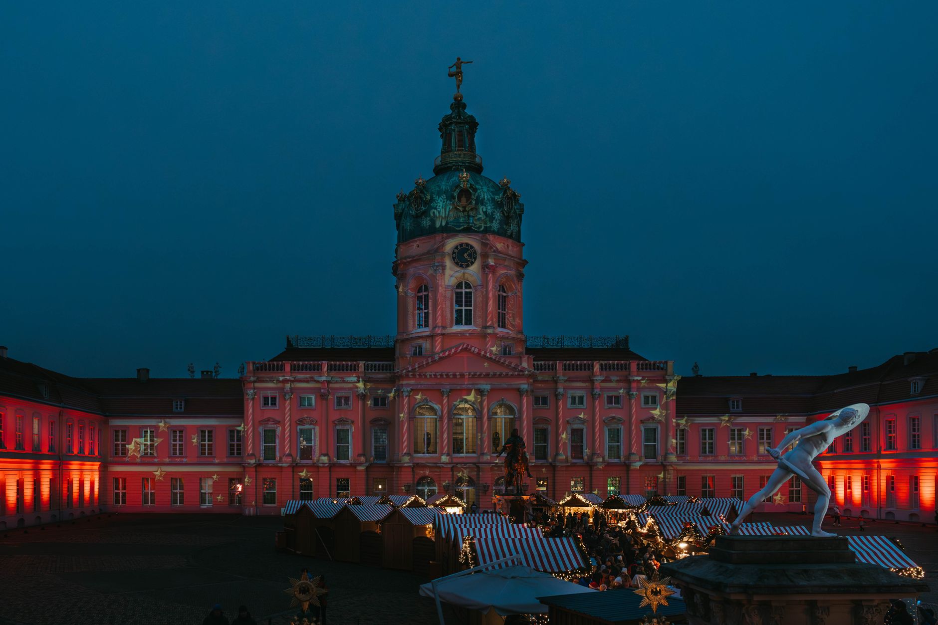 Evening view of the illuminated Charlottenburg Palace during a festival market in Berlin.