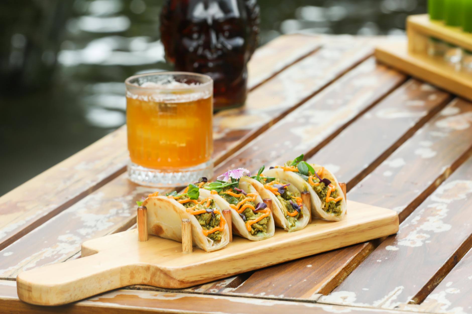 Mouthwatering tacos with a refreshing drink served outdoors on a rustic wooden table.