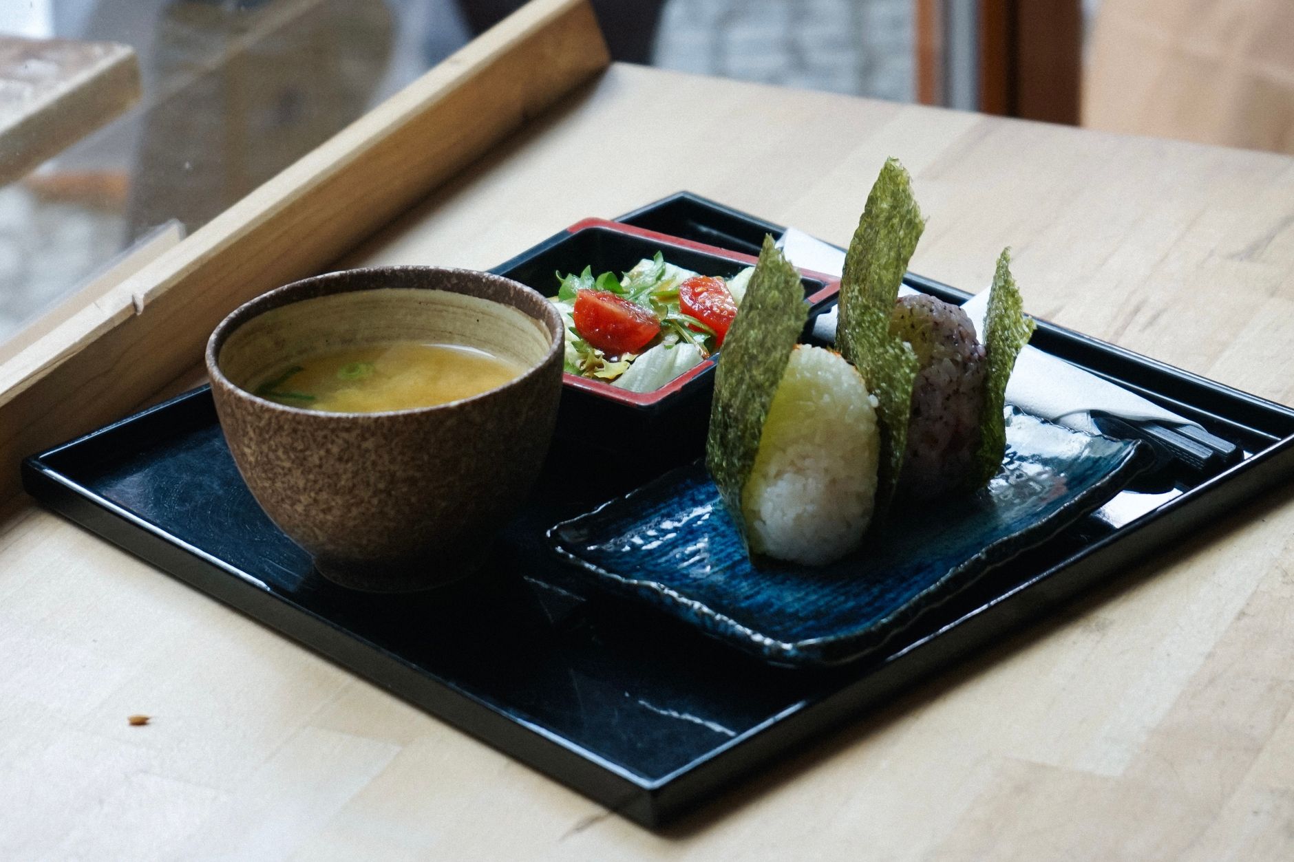Delicious Japanese meal with onigiri, miso soup, and salad served indoors in Berlin.