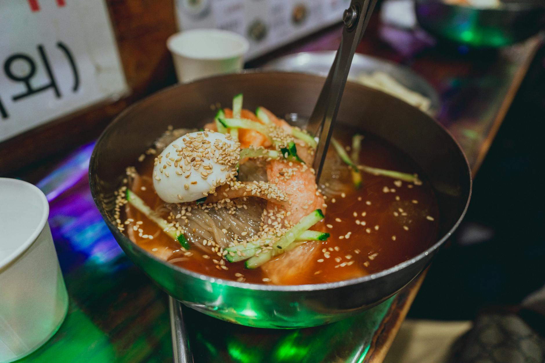 A close-up of Korean Naengmyeon topped with sesame seeds and vegetables in Seoul.