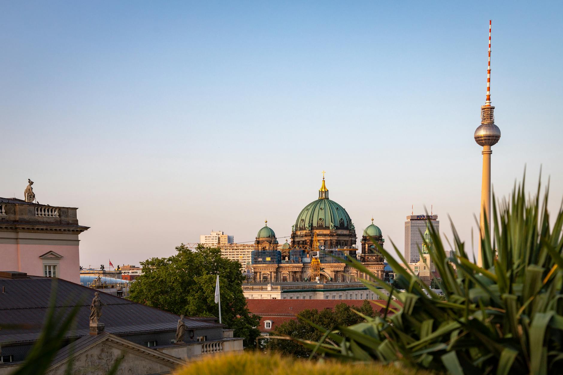 Beautiful view of the Berlin Cathedral and Fernsehturm under a colorful sunset sky.