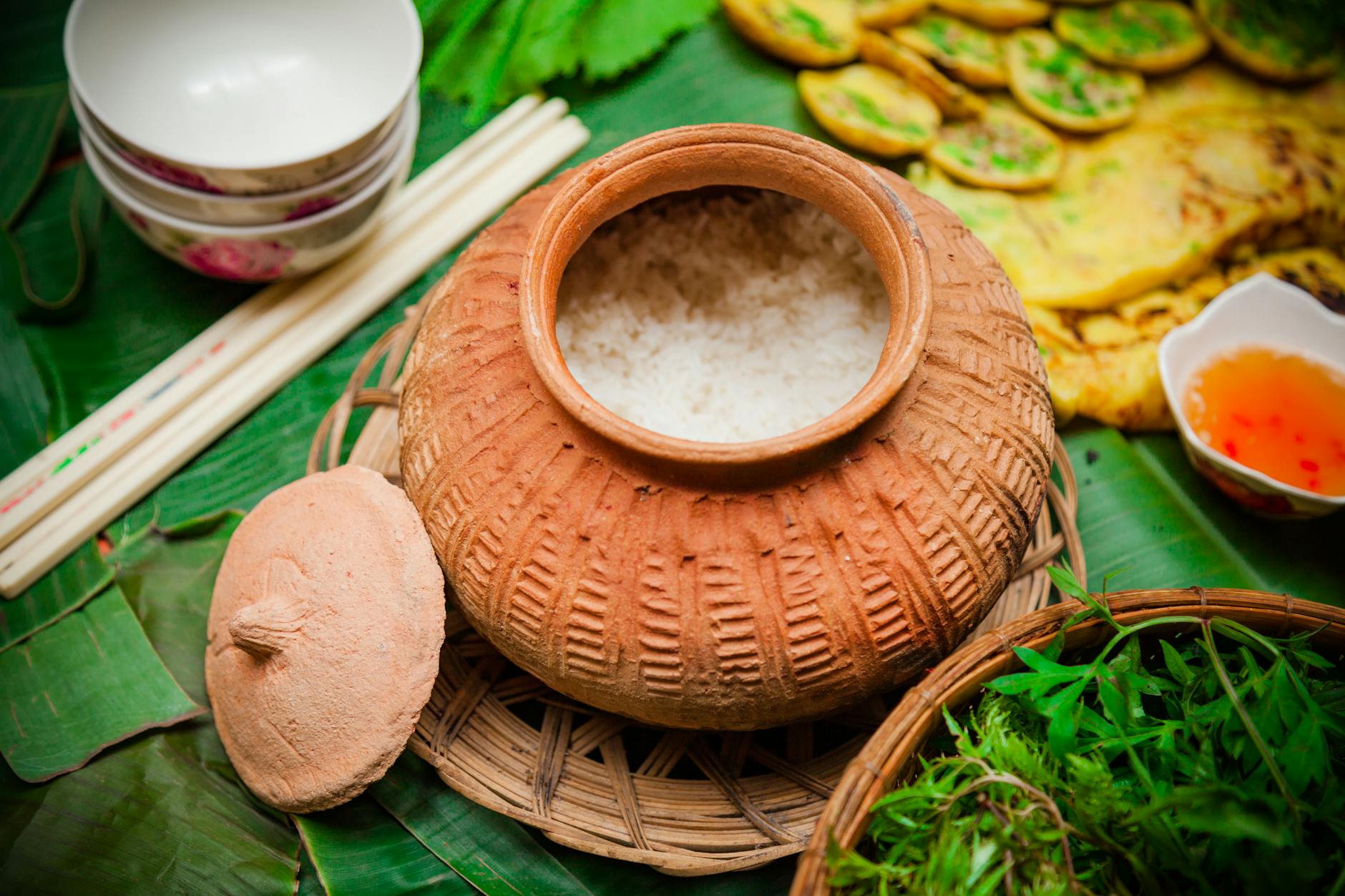 Discover the rich flavors of Vietnamese cuisine with a clay pot rice dish, herbs, and condiments.