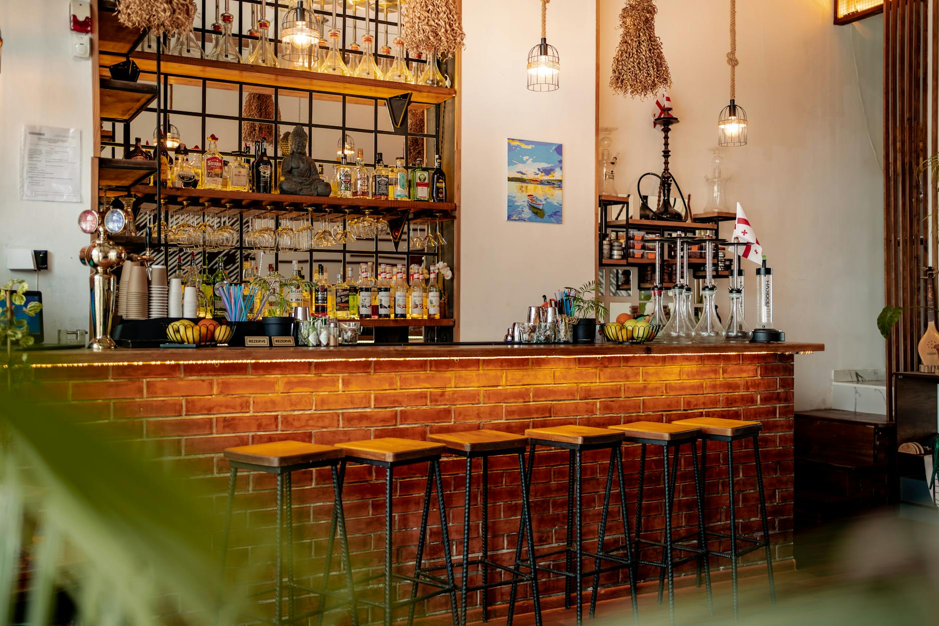 Warm and inviting bar interior with brick bar, stools, and hanging decor, perfect for a stylish night out.