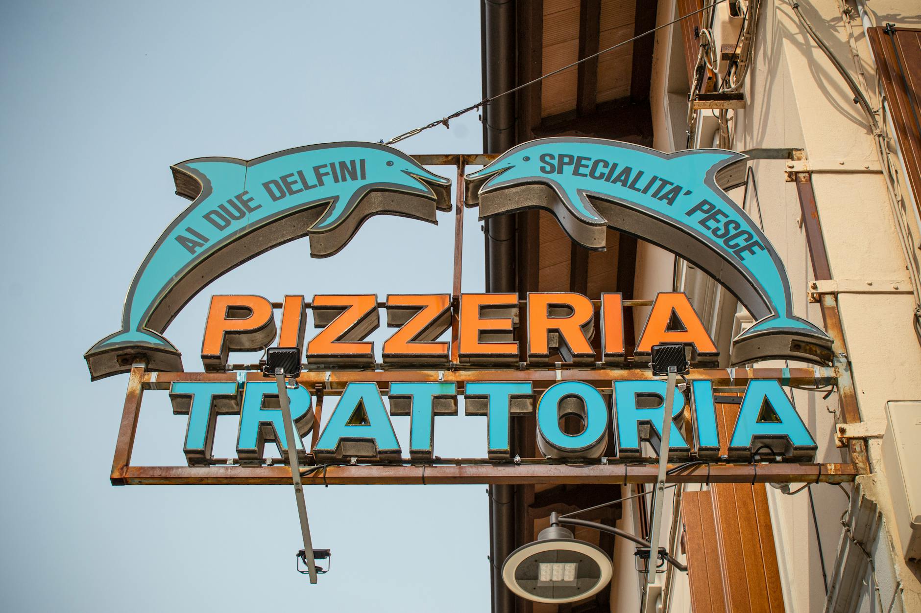 Vibrant sign for 'Ai Due Delfini Pizzeria' captured in Palmanova, Italy.
