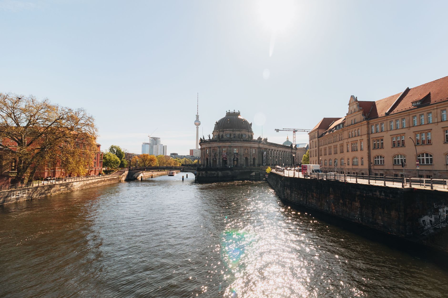 Captivating sunny view of Berlin's Bode Museum, Spree River, and iconic Fernsehturm with sparkling reflections.