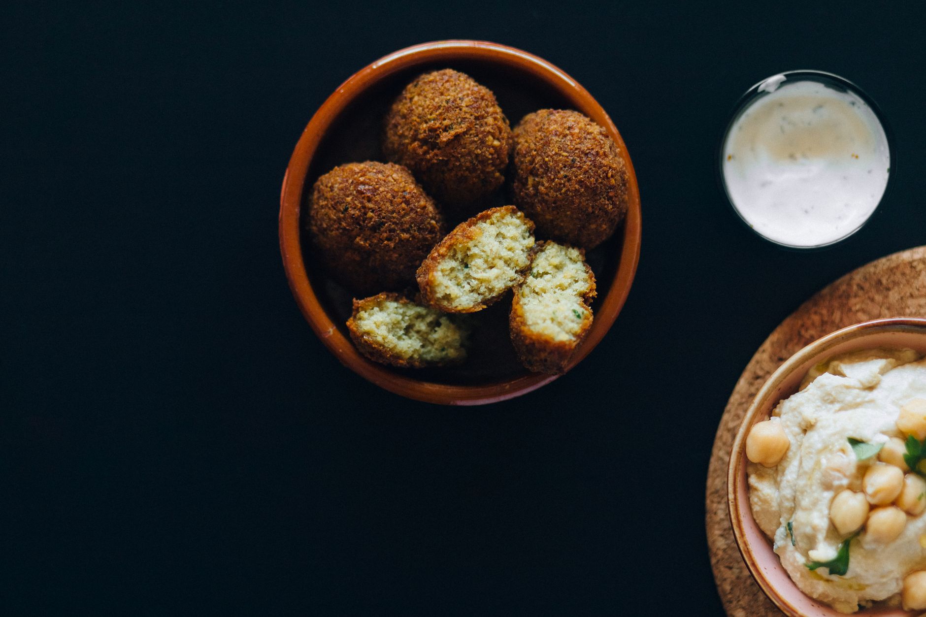 Delicious falafel and creamy hummus served with a side of tzatziki sauce, perfect for vegan meals.